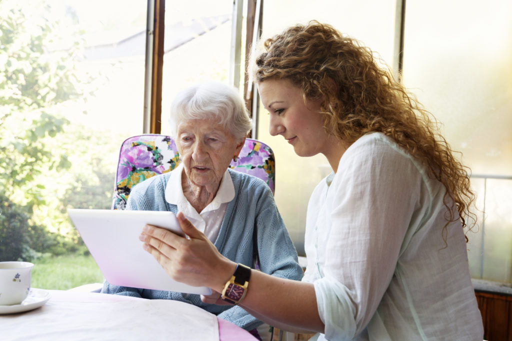 Senior woman and her caregiver lokk at a tablet PC together